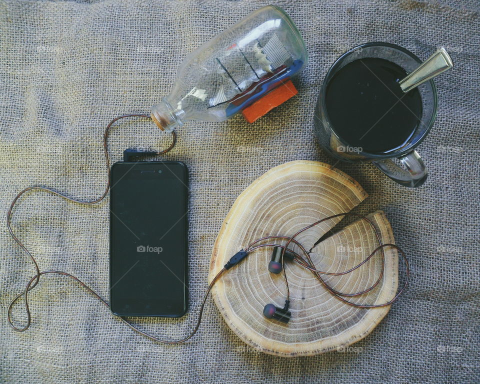 vacuum headphones on a cut-off tree, a smartphone and a cup of black coffee