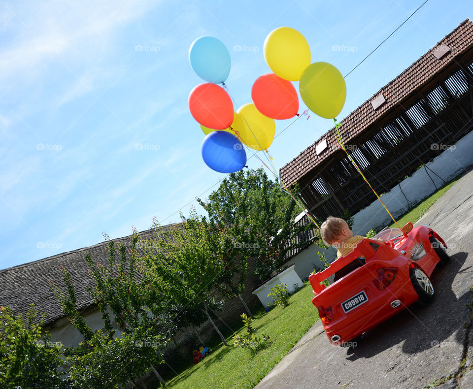 baby in a car with baloons