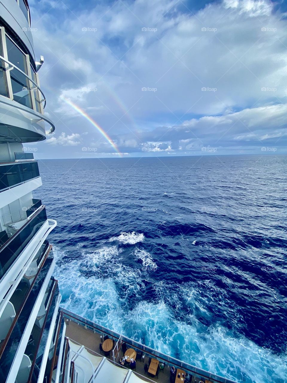 white waves in the blue sky against the backdrop of a double rainbow after the morning rain