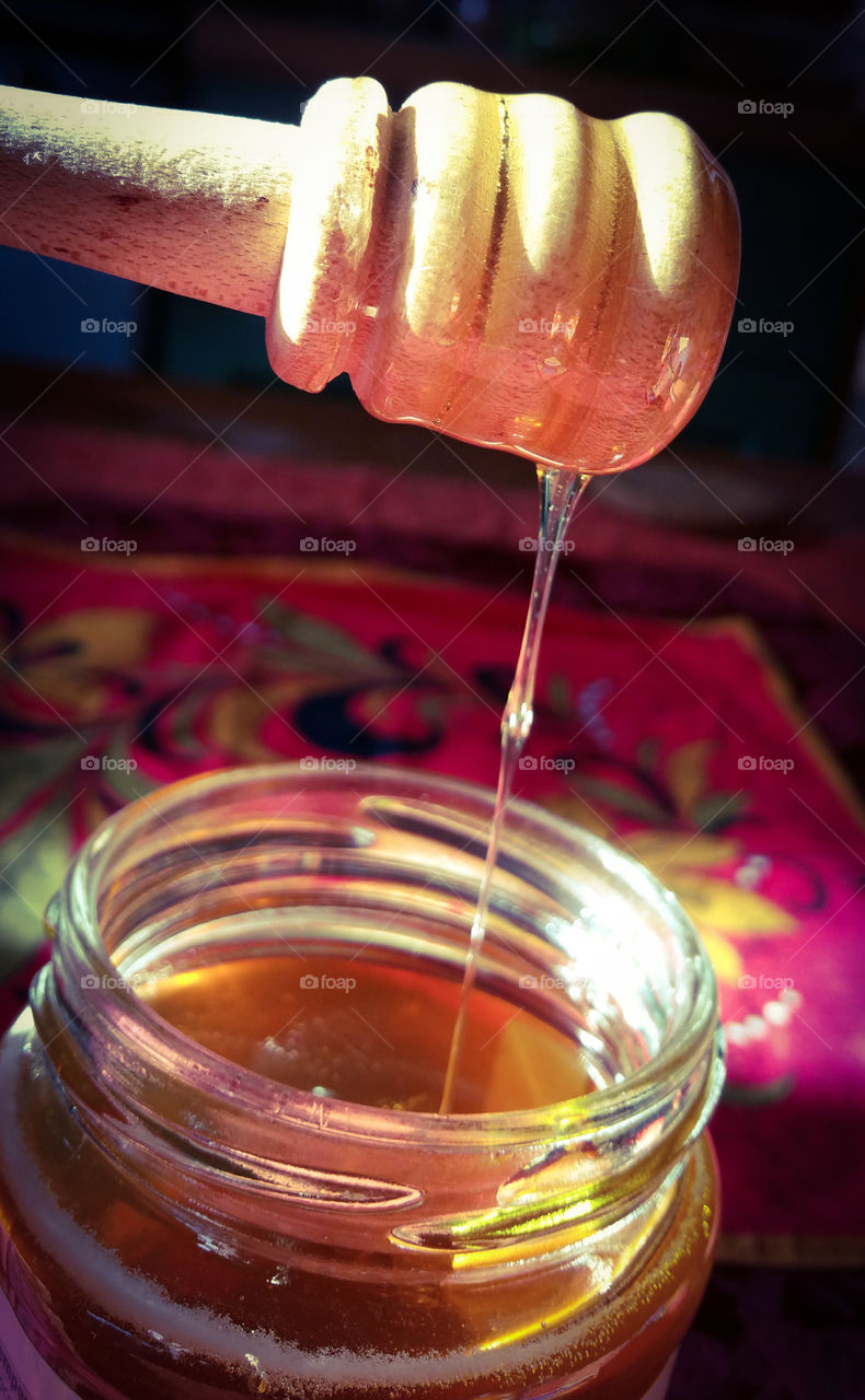 Honey in a glass jar with a  wooden spoon