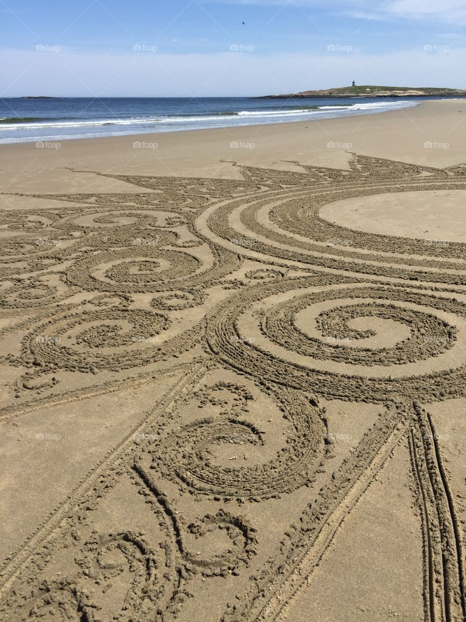 Sunshine artwork scrolled in the sand at Popham Beach in Phippsburg Maine USA. Artwork by Kathy Lambert. 