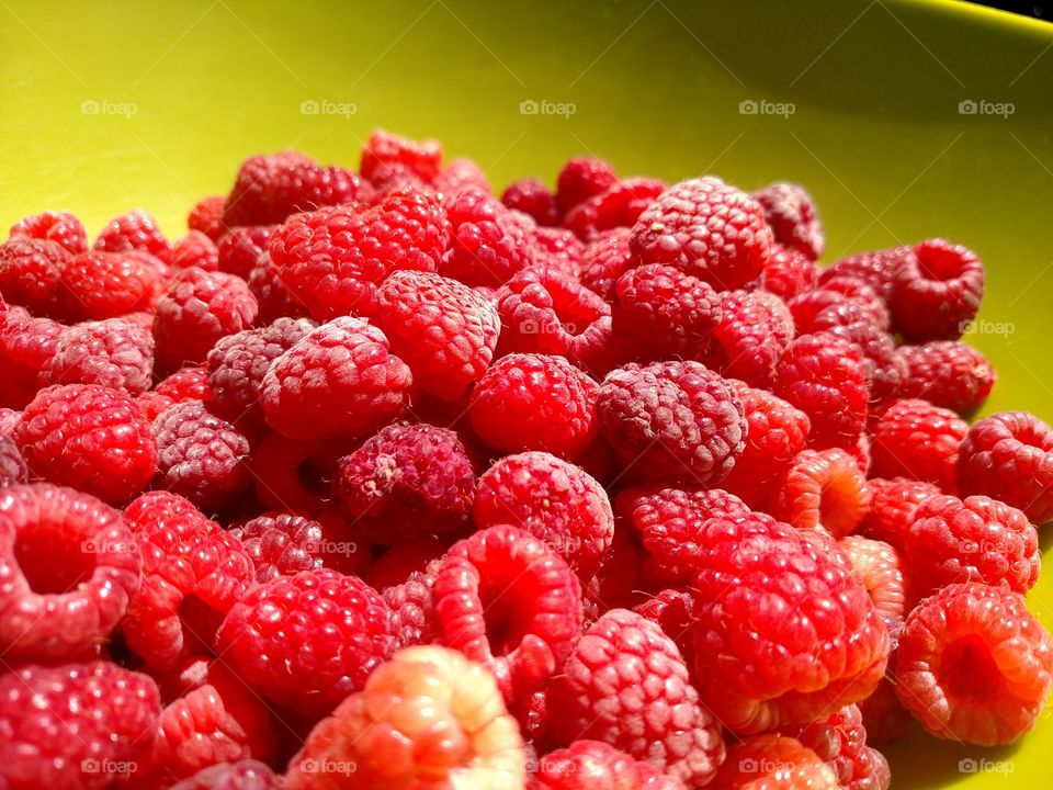 Raspberries in a green bowl.