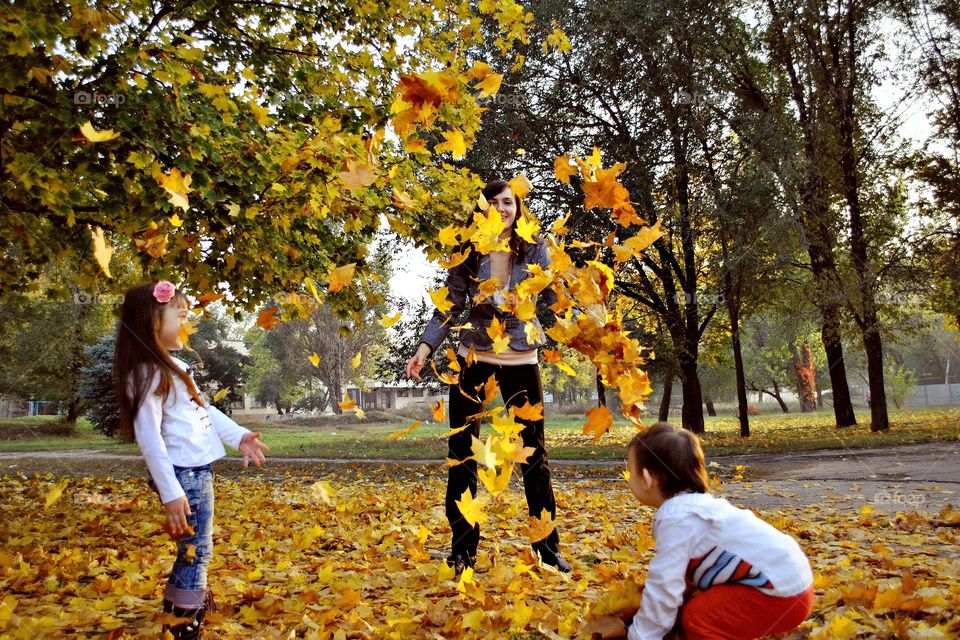 family playing in the park tossing leaves