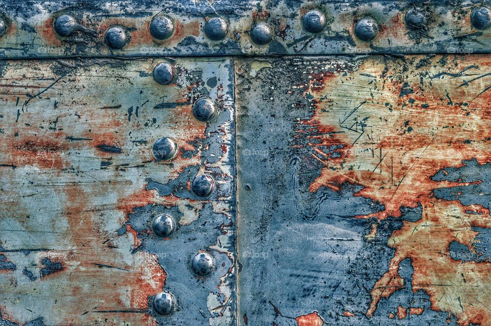 old metal peeled surface with traces of rust and abrasion complete paint. several sheets of metal are connected to each other with rivets. interesting background and metal texture