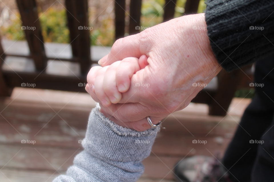 Elderly holding child's hands outdoors