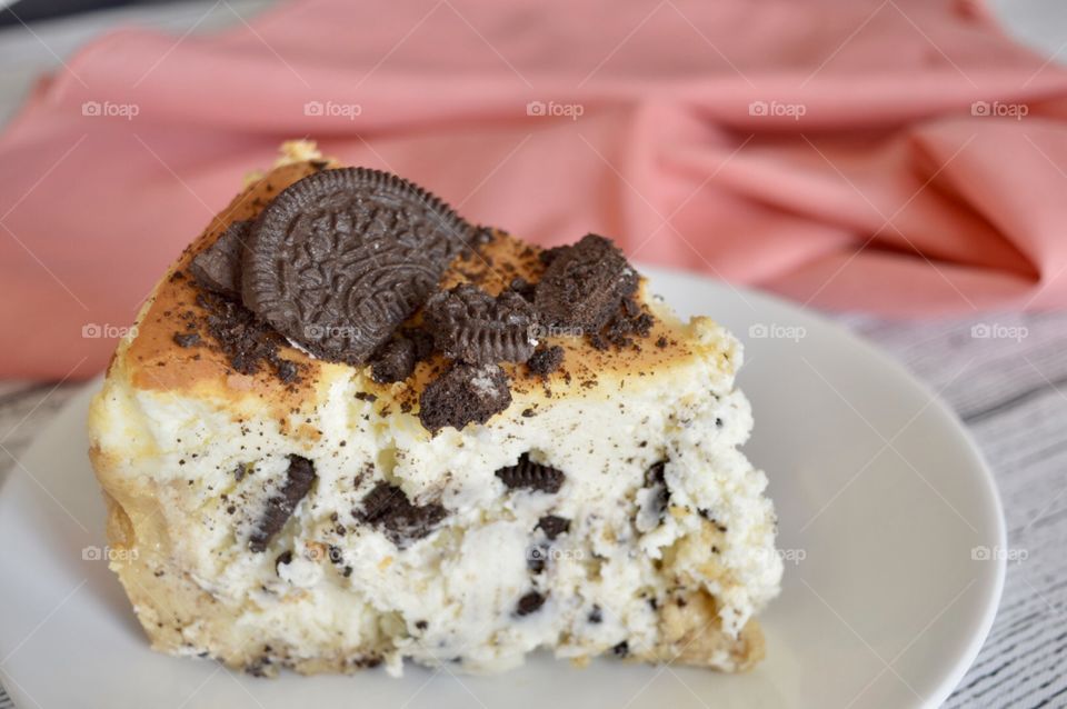 Oreo cookie cheesecake on a white plate with a pink napkin in the background