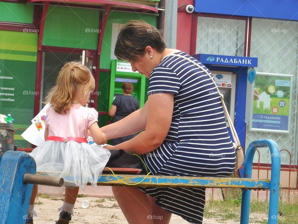 mother sits with her daughter on a bench