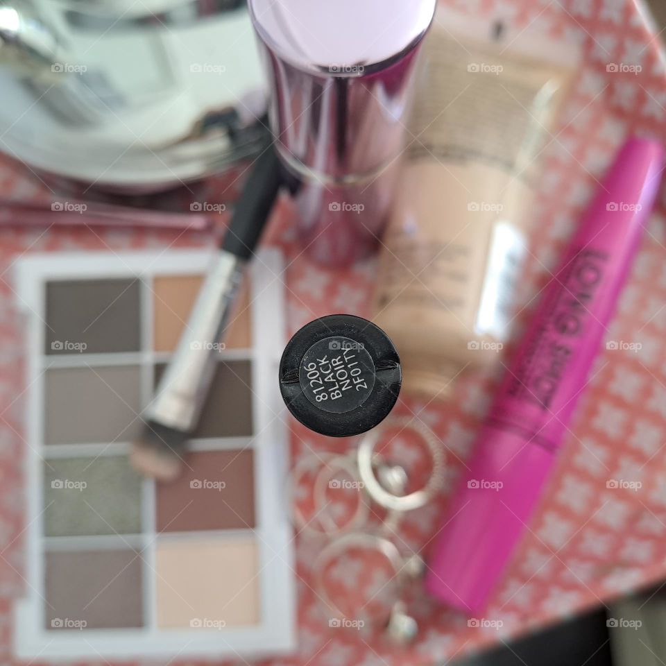 makeup on pink tray eyeshadow pallette mascara in background and black liner in foreground