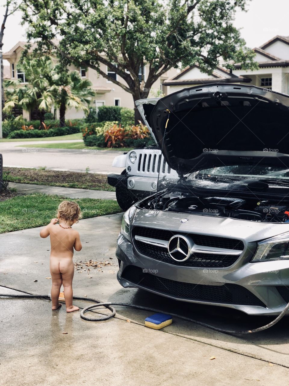 Small child helping wash the cars 