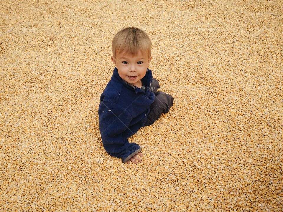 Child playing in corn pit