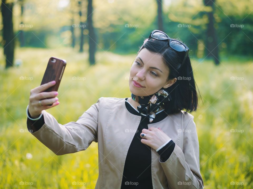 Beautiful woman taking selfie with her smartphone in the park 