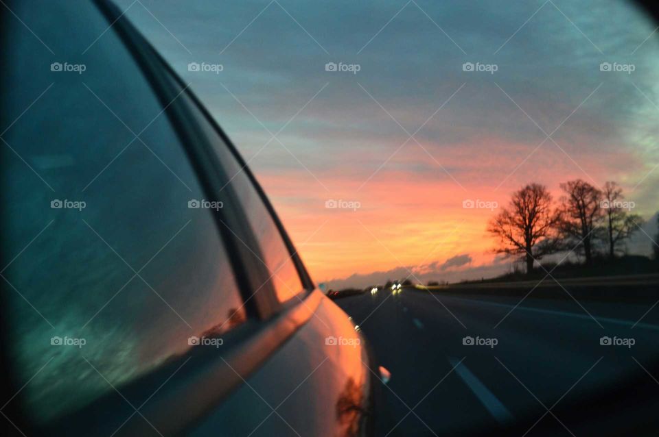 Colorful sunrise in the wing mirror in Alfa Romeo 159 car on the expressway in Poland