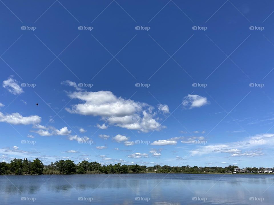 White, puffy clouds in a true blue sky over Twilight Lake in Bay Head, NJ. They are so low in the sky, you feel like you can touch them. 