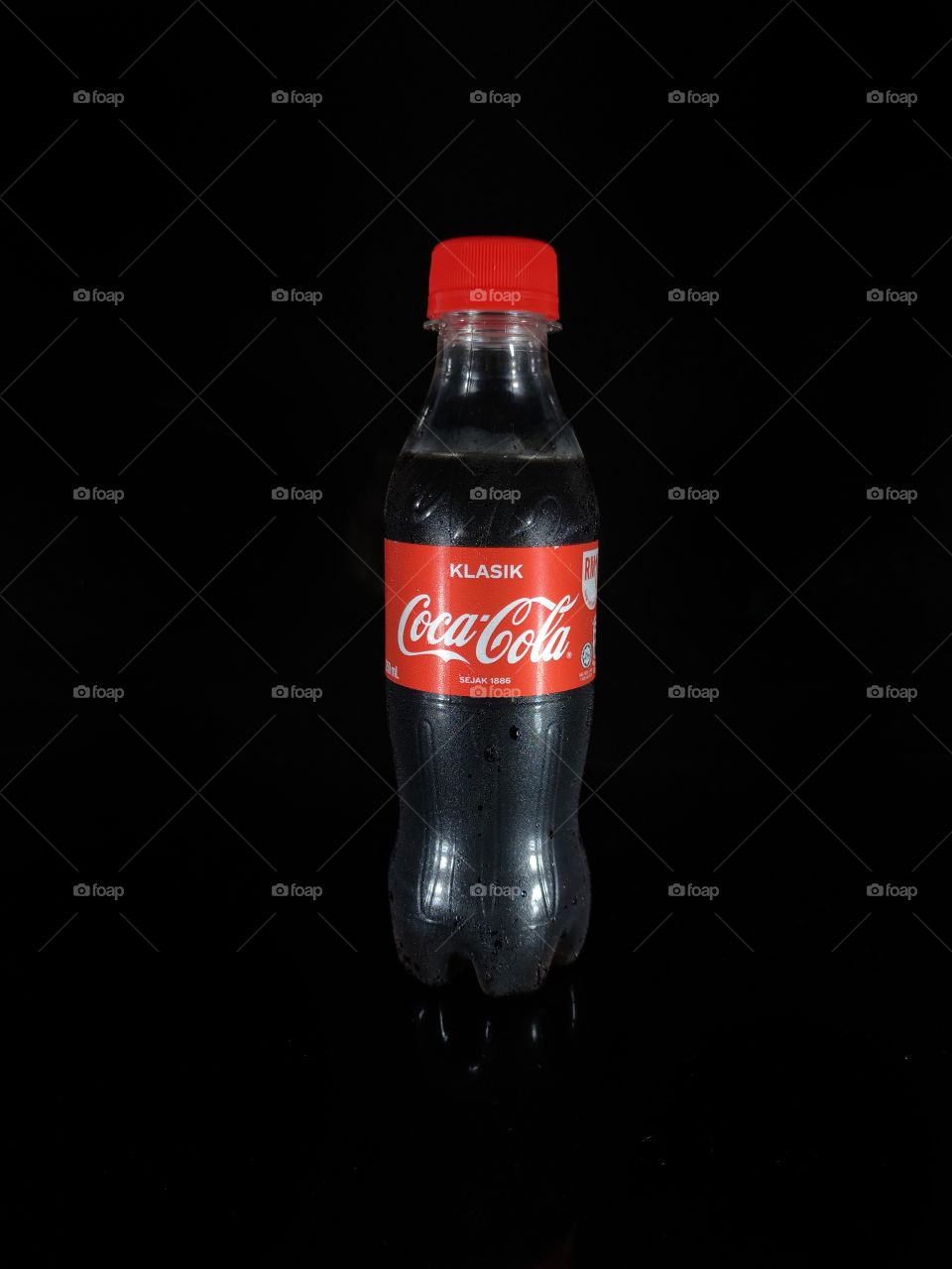 A bootle Coca cola classic with reflection  on a black background.