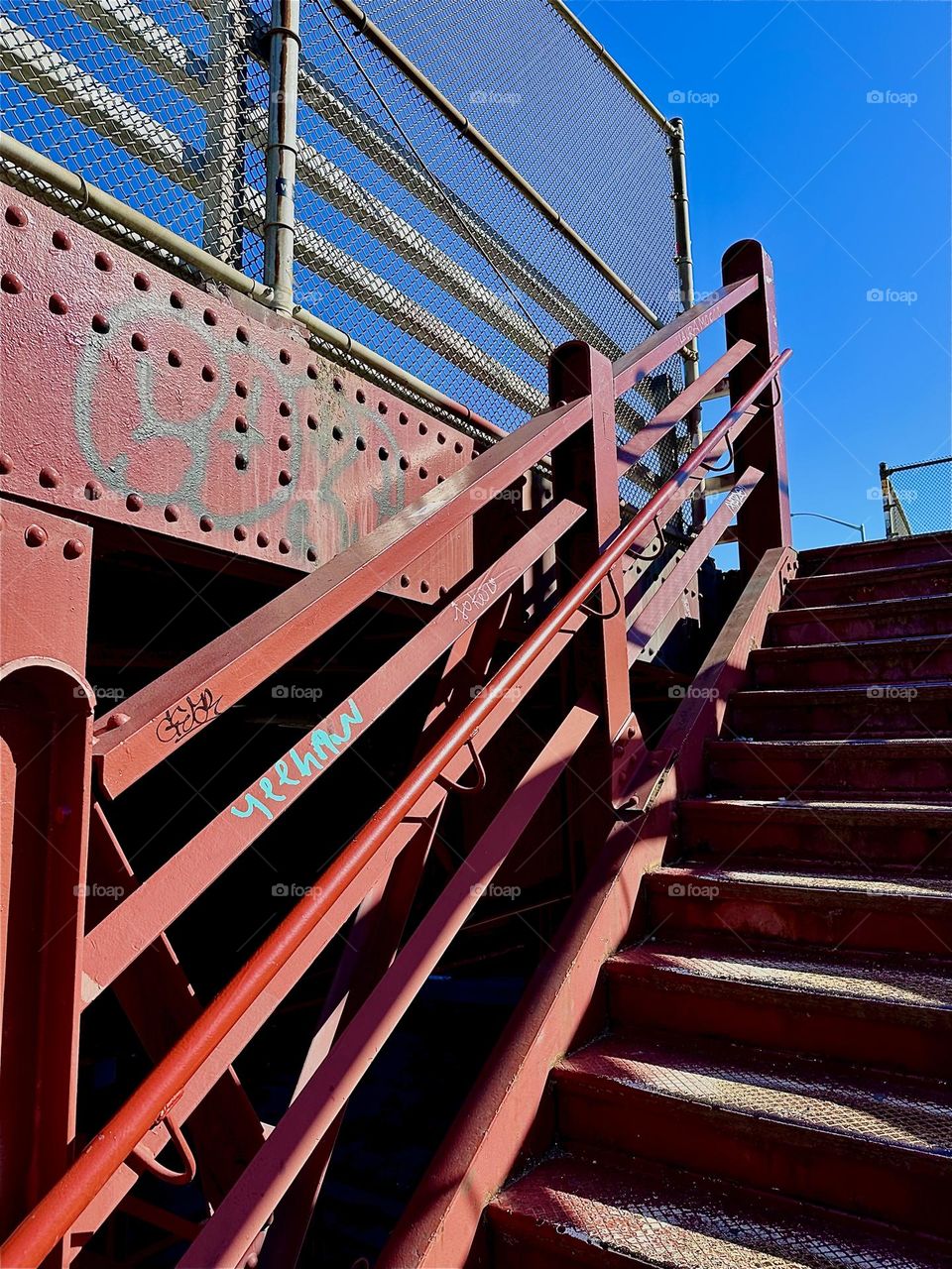 This is the red metal staircase of the “Pulaski Bridge” at “Newtown Creek” in “Greenpoint”, Bklyn, NY. Its style reminds distinctly of the early modern architecture of the “Bauhaus” school in “Weimar”, Germany of the 1930s. 2024. Hypnotic Productions