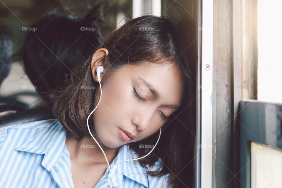Relax time of asian young woman sleeping and listening music in earphones during trip on the train.jpg