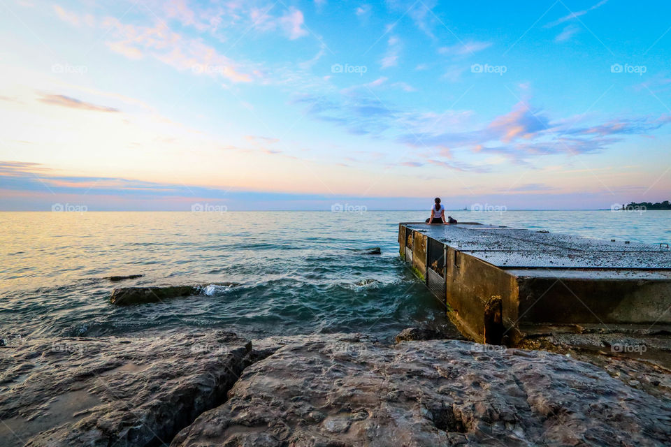 Woman meeting sunrise sitting on a pier