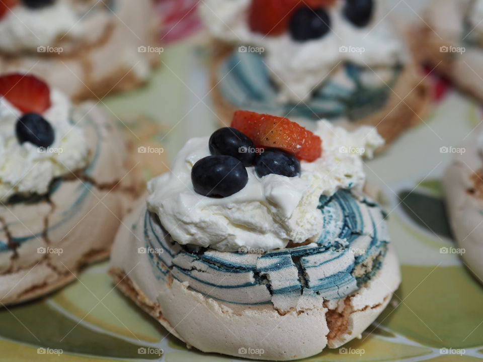 Blue swirled meringues with strawberries, blueberries and cream