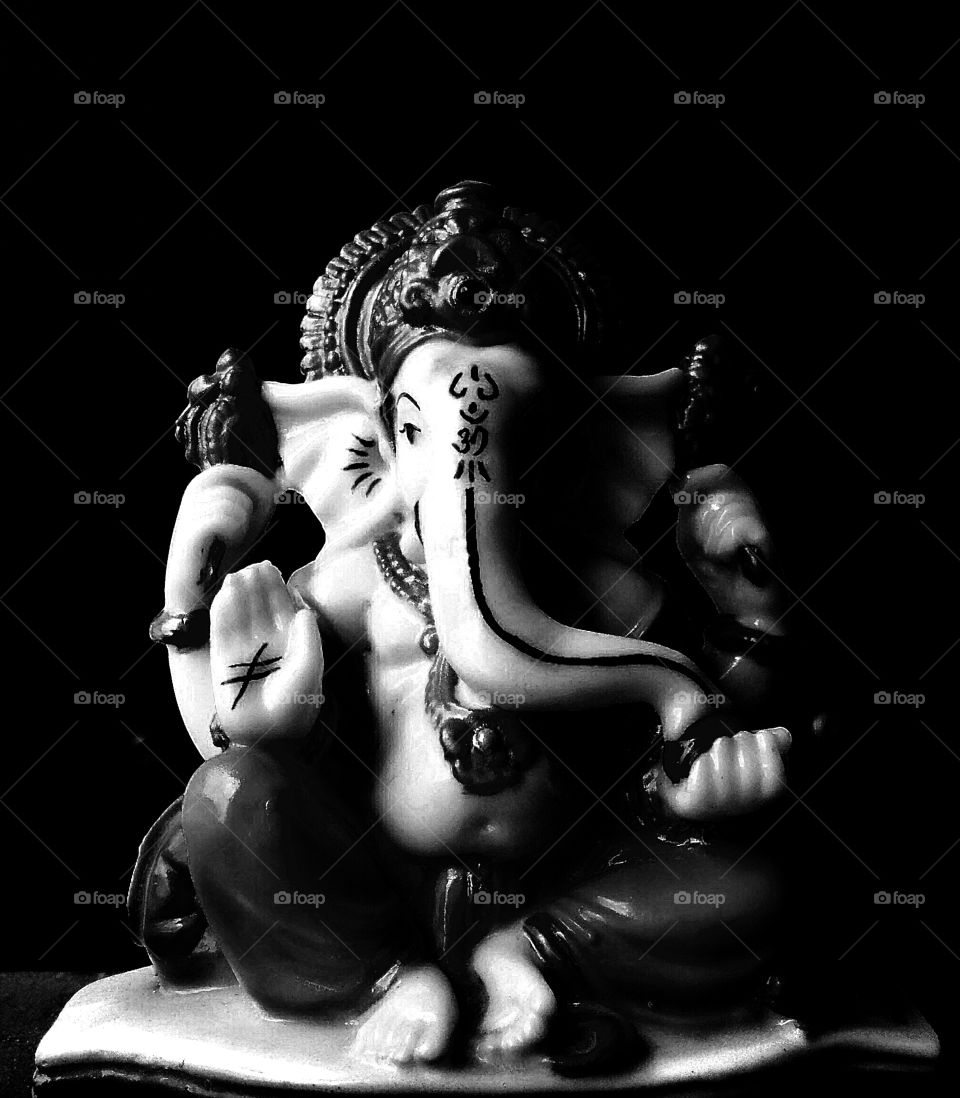 Statue of Indian Lord Ganesha in black and white colour having black background.