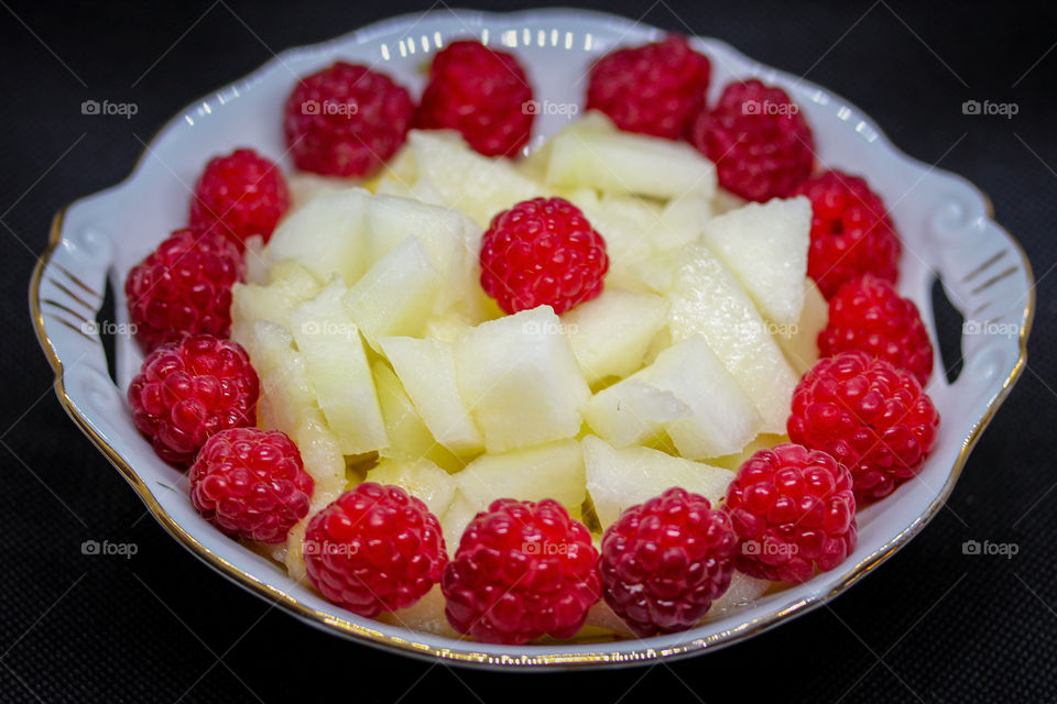 red berries and slices of a melon at the plates