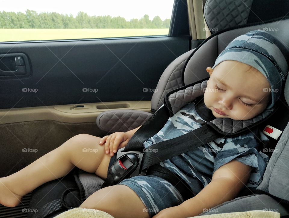 a little boy sleeps in a car seat