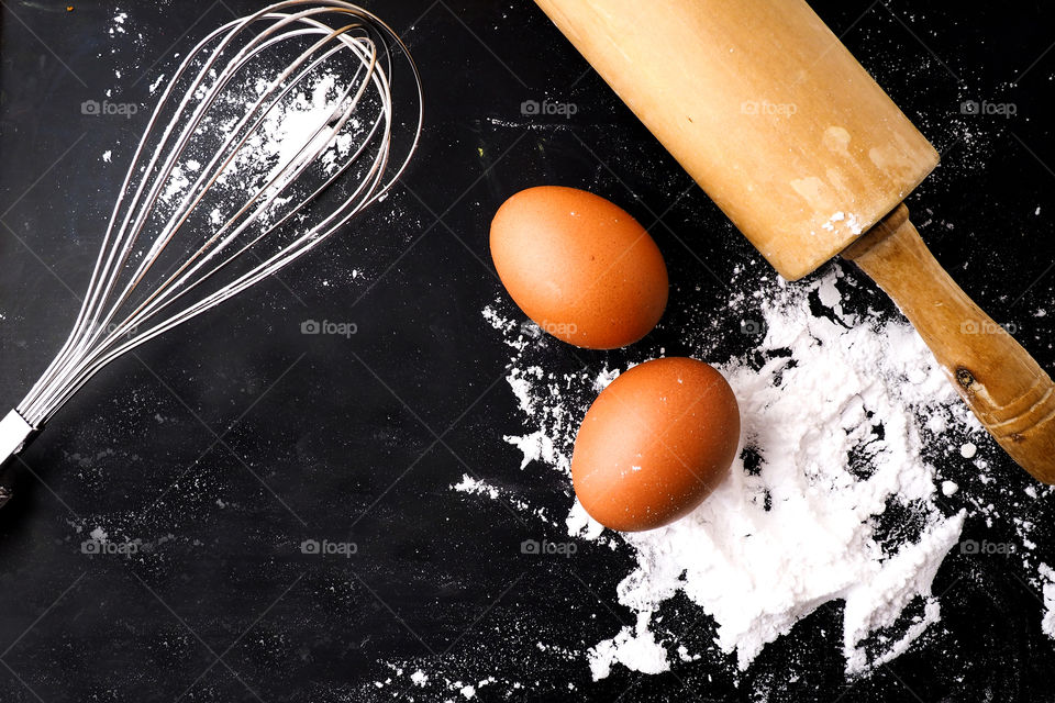 Top view of molder, flour and eggs on black background