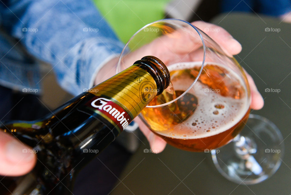 Beer from a beer bottle is poured into a glass.