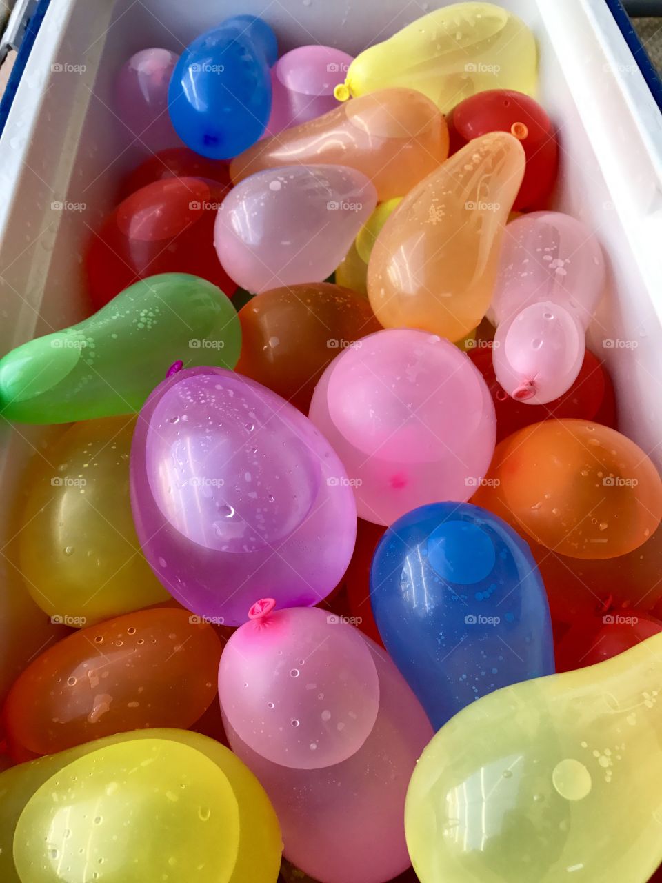 Cooler filled with colorful water balloons 