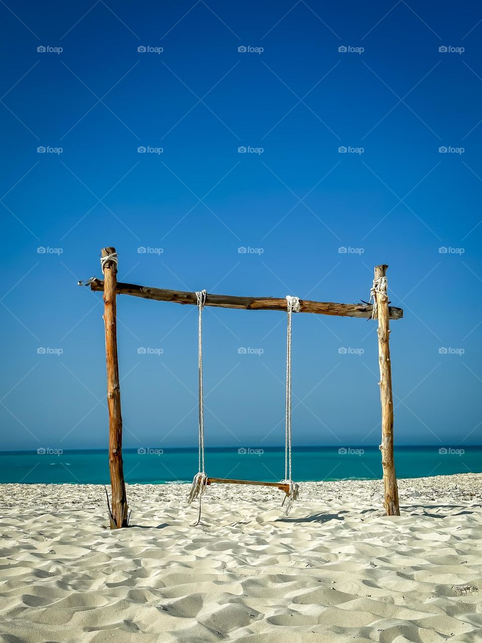 The last days of summer. A wood and and rope swing on a white sand beach on the Mediterranean coast of Egypt.