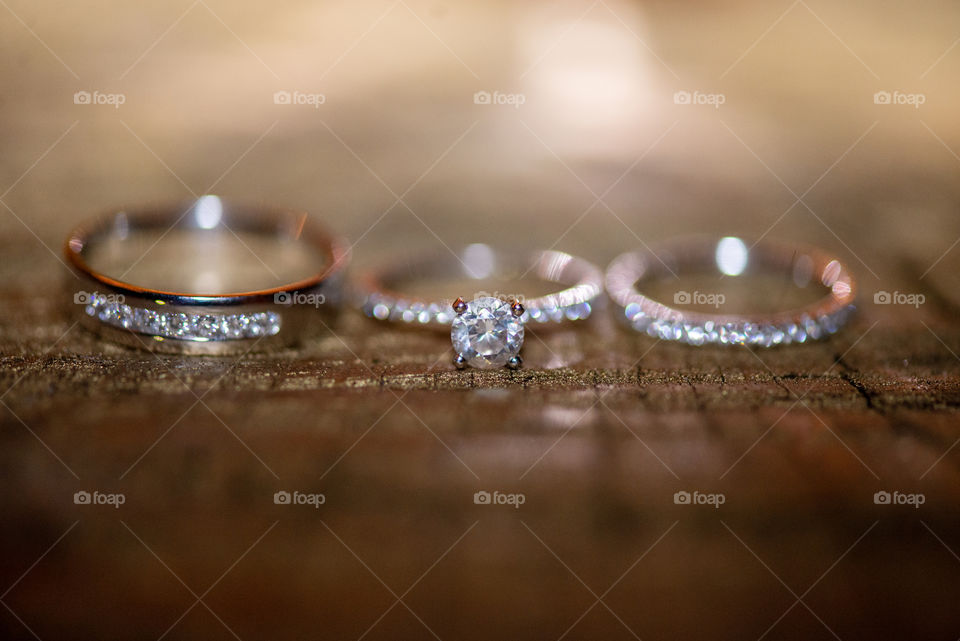Brides engagement ring and diamond wedding band on wood surface