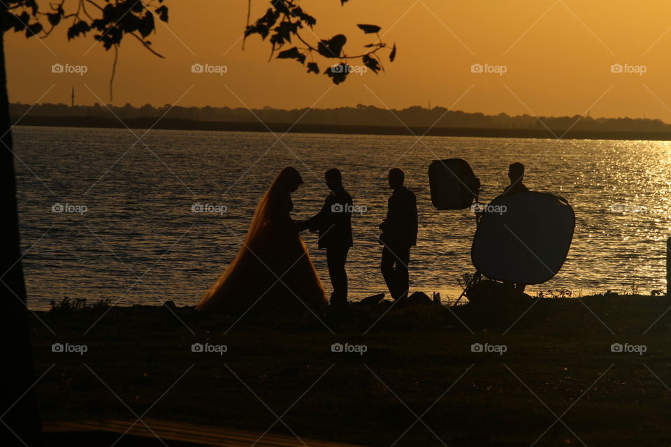 Love of the sunset

I was traveling near lake and I saw that couple while taking wedding photos. I captured them.