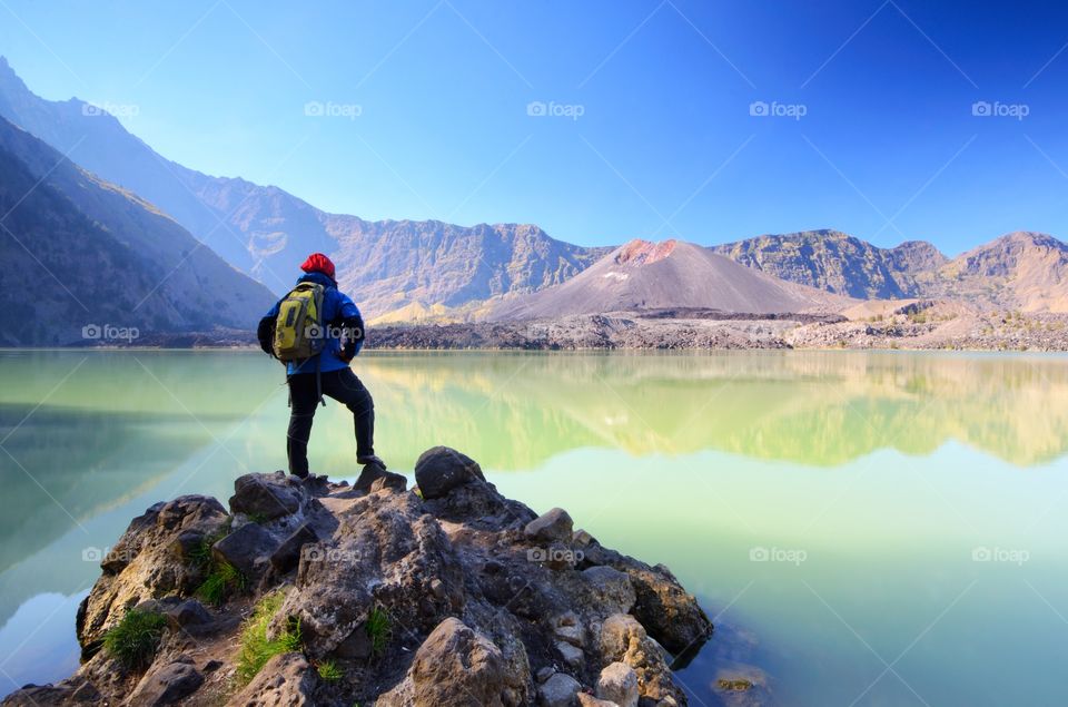 Beautiful nature background with unidentified hiker at Segara Anak Lake in early morning. Mount Rinjani is an active volcano in Lombok, indonesia. Soft focus due to long exposure.