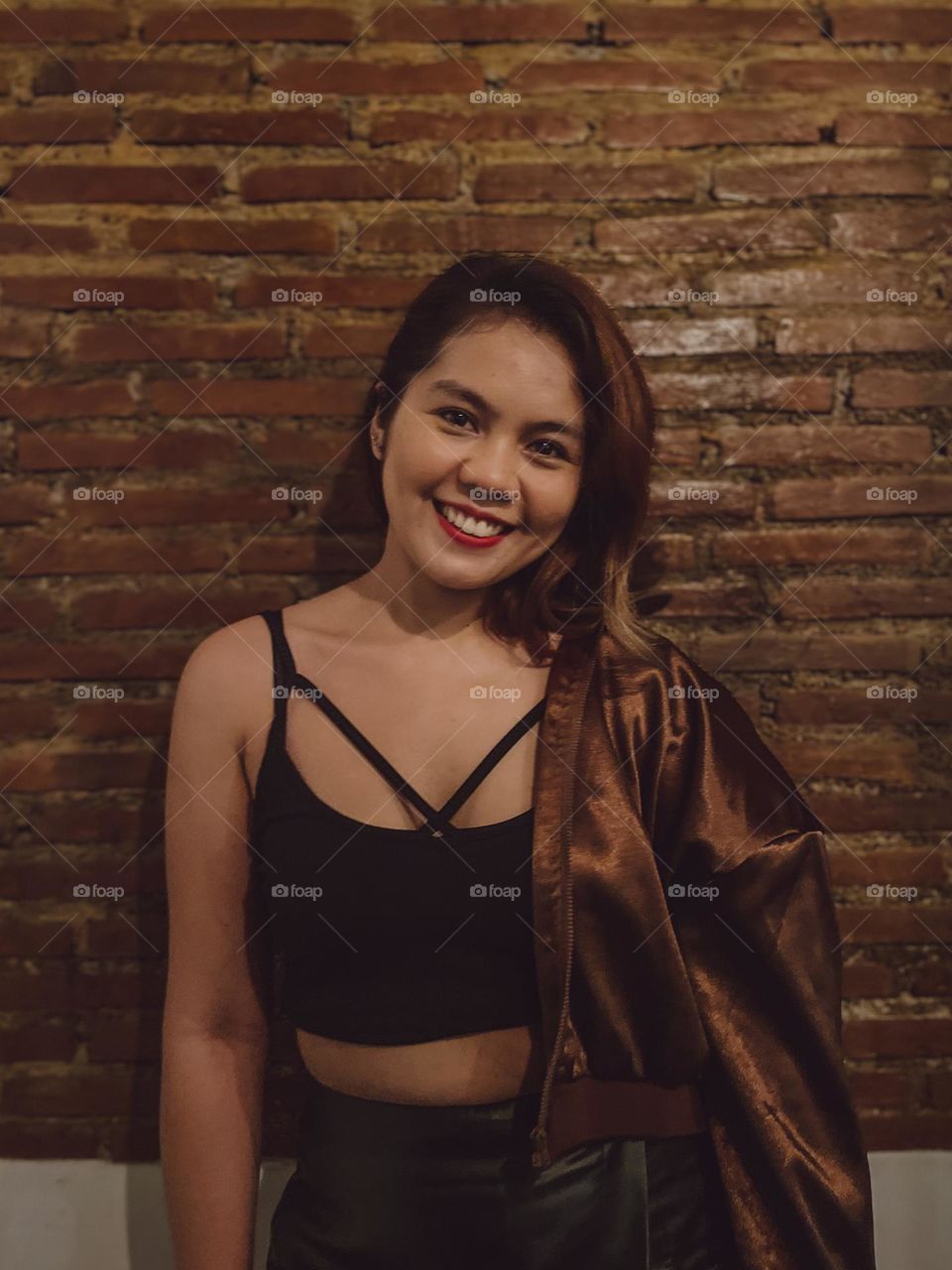 A portrait of a girl smiling with bricks on the background