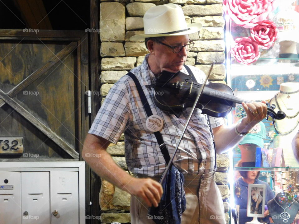 country man playing brown violin in overalls