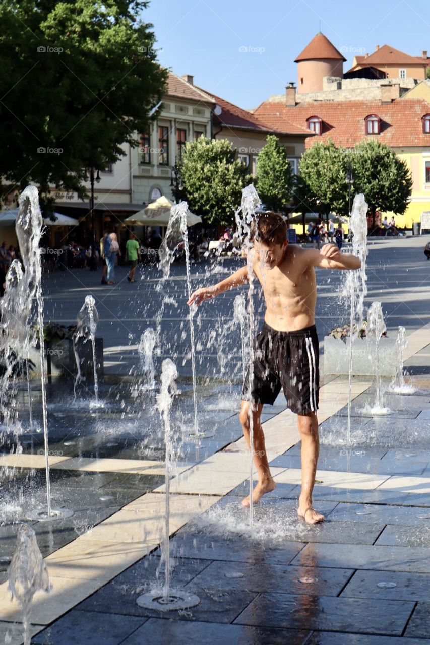 Kid get wet in street water fountain 