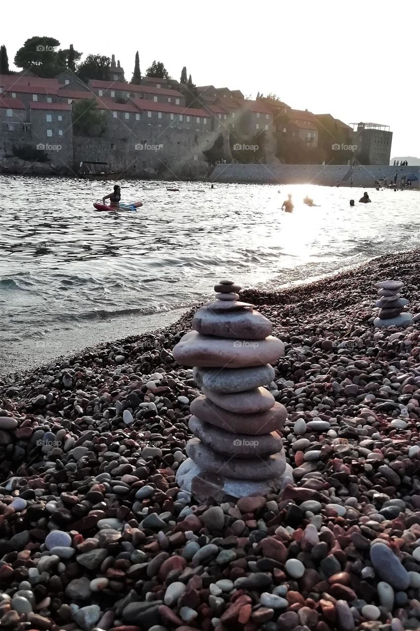 The beach at sunset is almost empty. How nice it is, to watch the sunset and build stone towers on the shore.