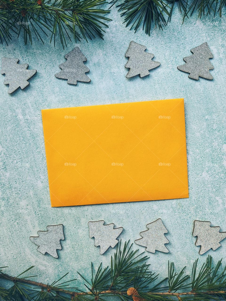 Christmas or New Year composition.  Paper yellow envelope with fir branches on a blue background. Flat lay. Top view.