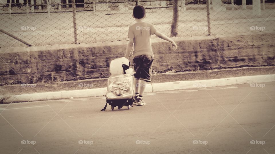 Criança com bolsa escolar, de rodinha.