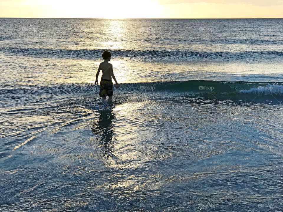 Boy in the ocean sunset.