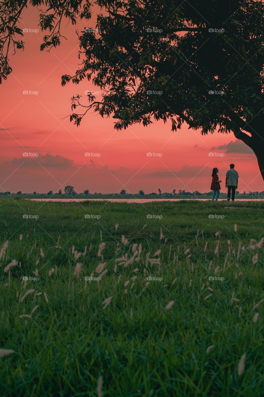 Father and daughter enjoying the sunset at river side