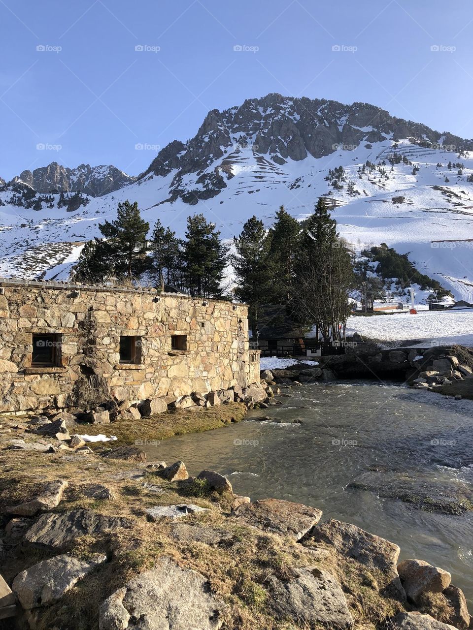 Stone house close to the water and the mountain covered by snow 