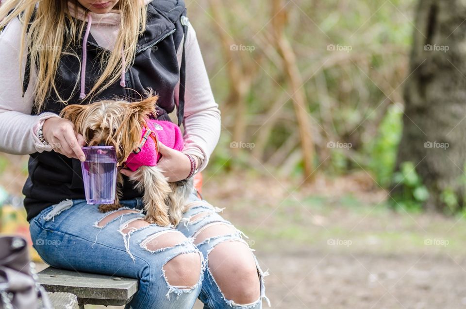 A girl helps her pet dog to drink water
