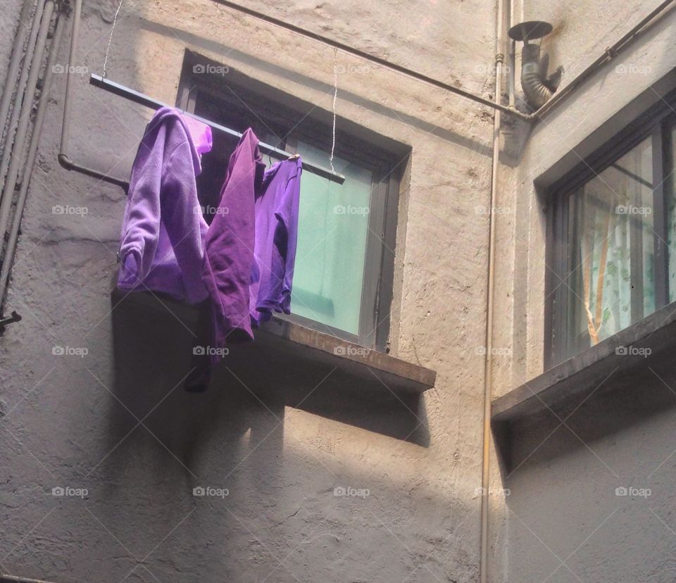 Purple clothes hangin out of a window.