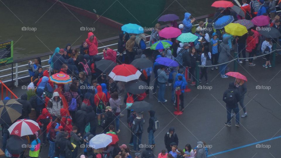 People waiting to get on ferry with colorful umbrellas
