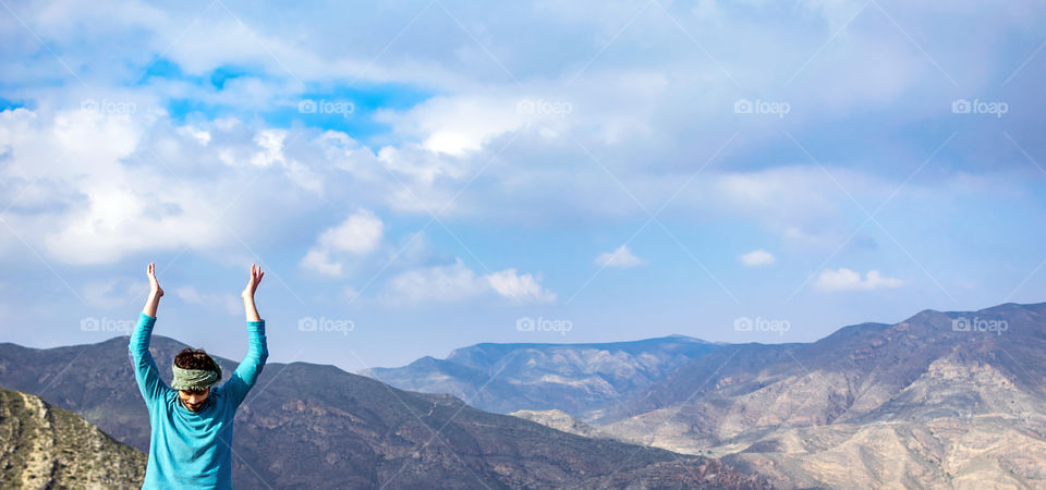 Indian man practicing the Yoga position Sun salutation over a cliff in nature