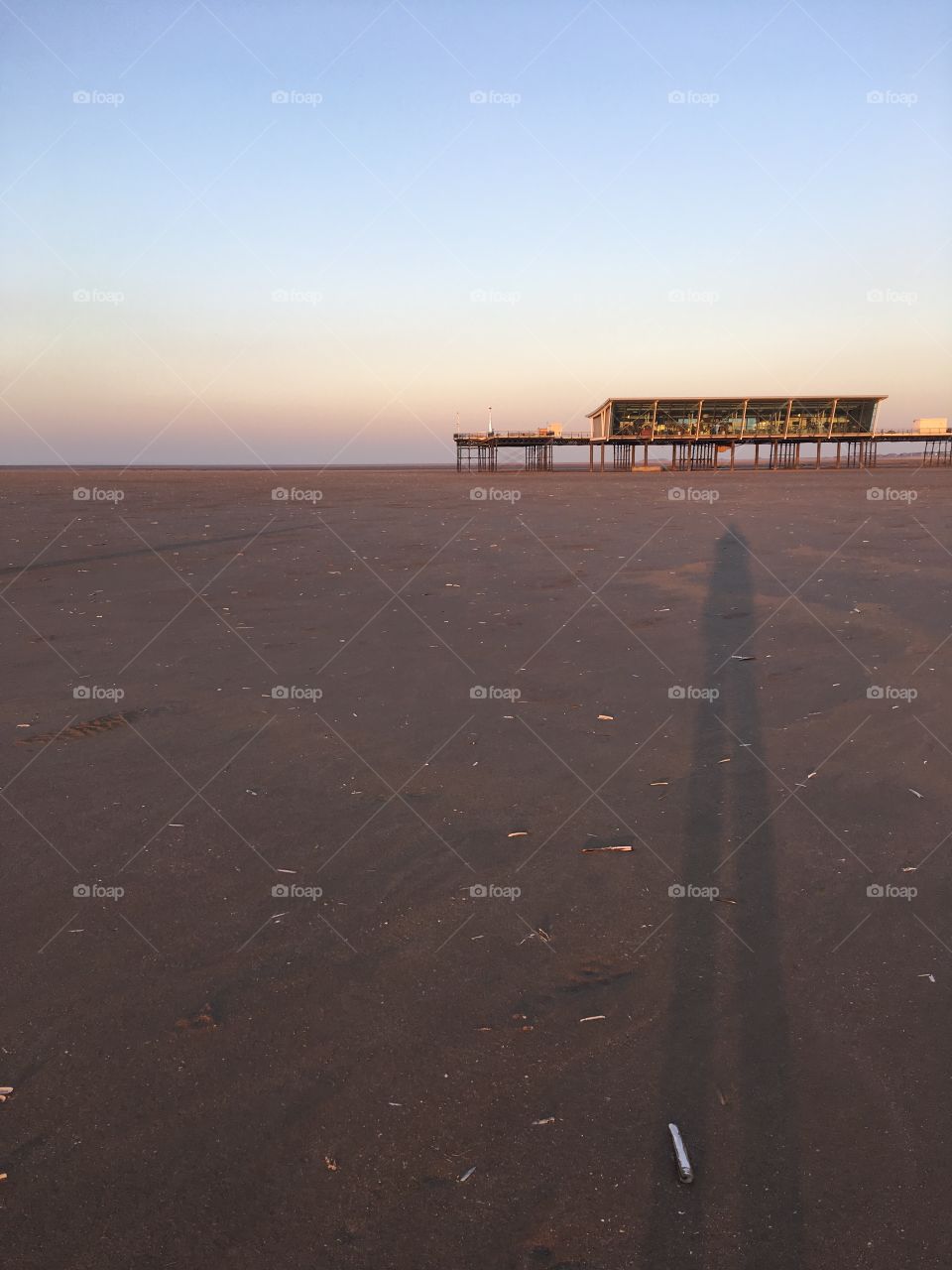 Southport beach at winter low tide as the sunsets and casts long shadows towards the pier 