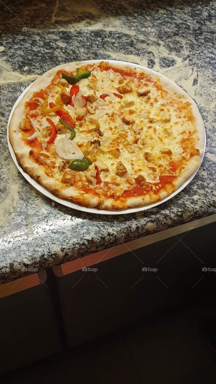 pizza, half with chicken, the other half with peppers, onions