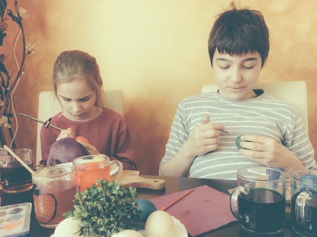 Brother and sister painting Easter eggs at home