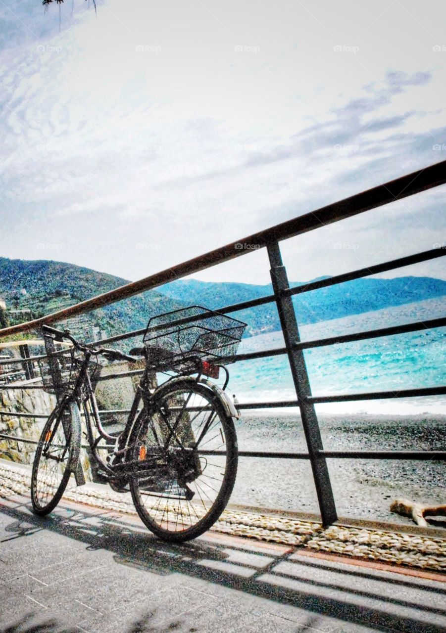 Beach bike. A bike rests on a railing above a beautiful beach