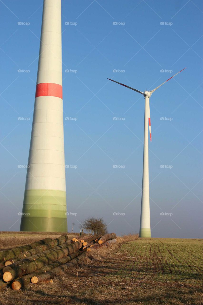 two Wind turbines and a wood stack
